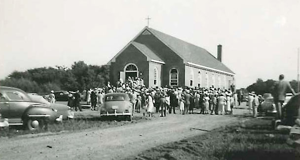First service at St. Martin's-in-the-Field's new church in June 1955. Image shows the front of new church from the outside and everyone entering the building.