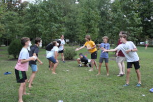 Youth standing on lawn participating in throwing game.