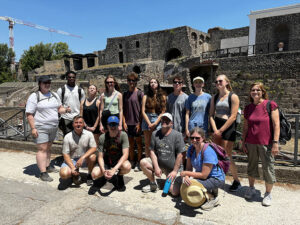 Adults and youth stand in front of ruins in Greece.